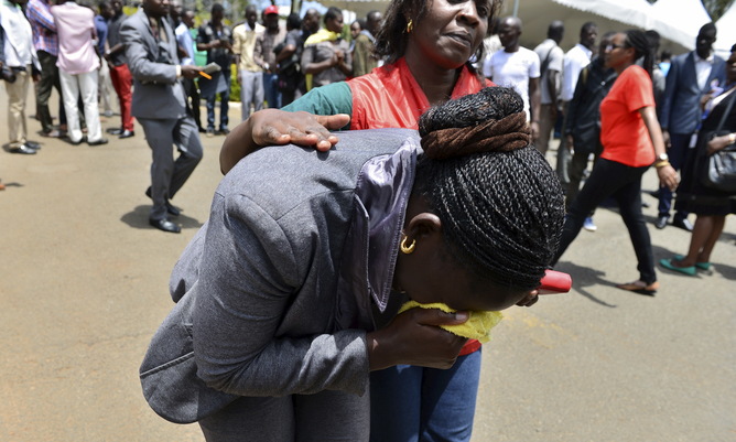 A relative is assisted by Red Cross staff as bodies of the students killed in Thursday's attack by gunmen, arrive at the Chiromo Mortuary in Nairobi